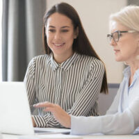 Ceo female in glasses show to intern millennial girl corporate program task use pc, senior woman executive leader supervising teaching colleague, mentor share knowledge helping to new employee concept